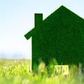 A felt cutout of a house standing on grass.